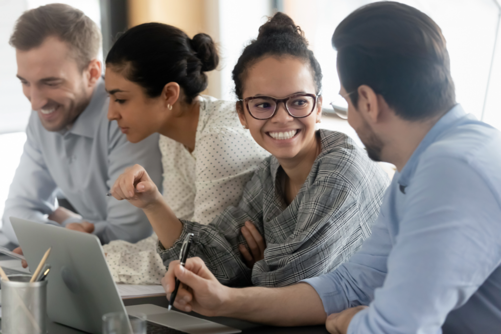 Smiling woman in glasses engages with colleagues during a collaborative office discussion.